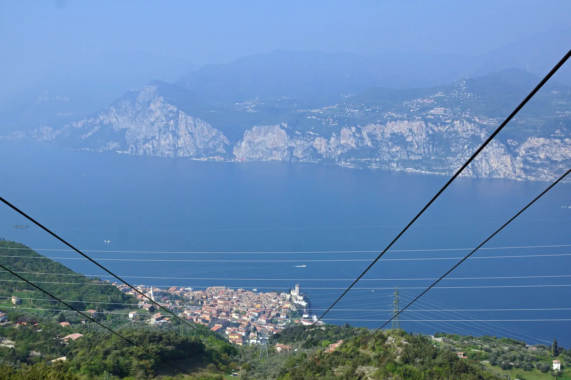 Blick von der Seilbahn Malcesine–Monte Baldo über die Tragseile hinunter auf Malcesine und den Gardasee