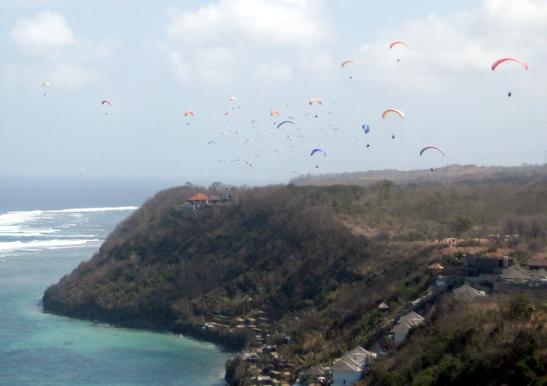 Dozens of paragliders soaring above the sea cliffs at Timbis on Bali's Bukit Peninsula