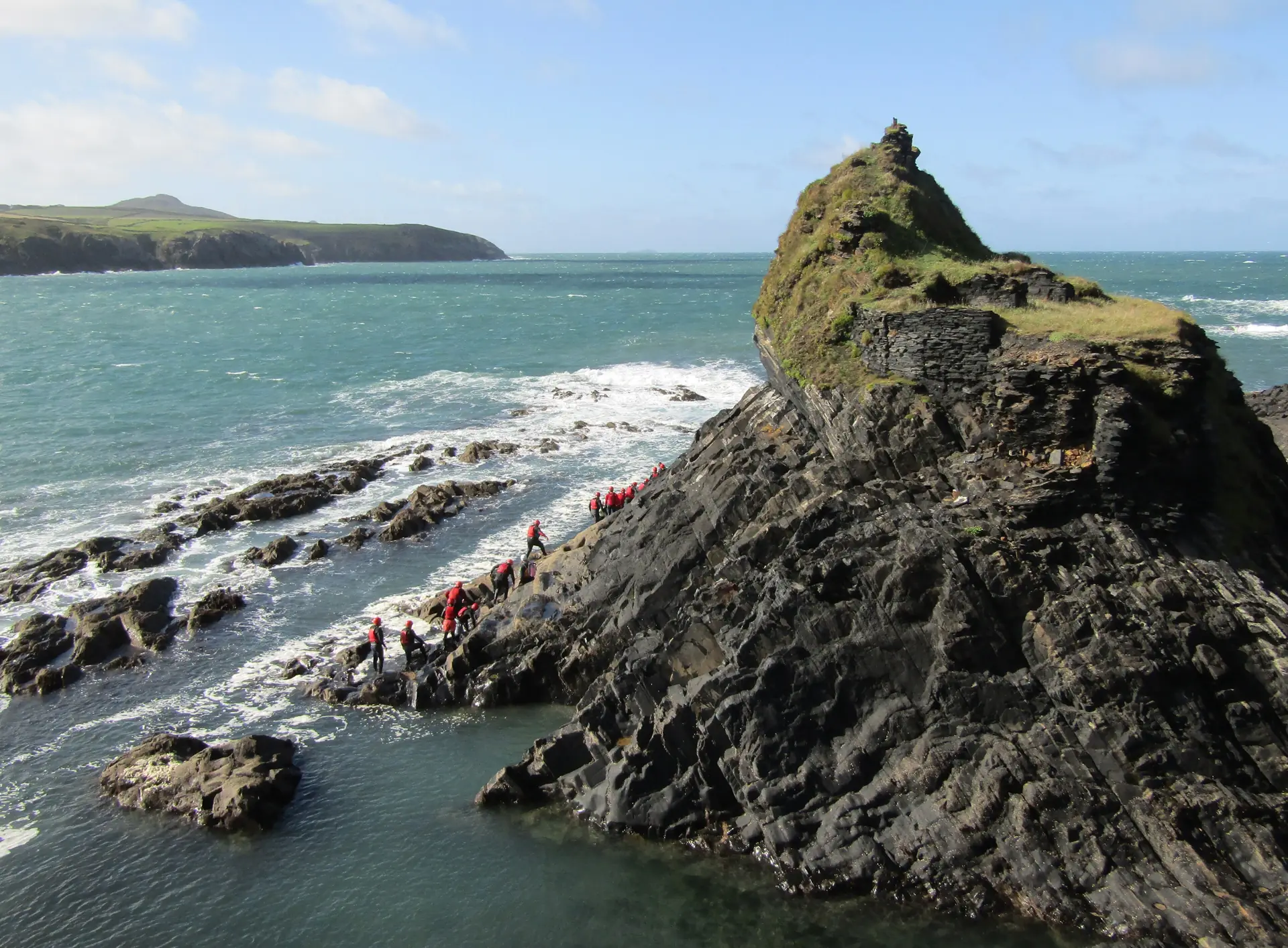 Eine Coasteering-Gruppe in Neopren an den Felsen der Blue Lagoon von Abereiddy