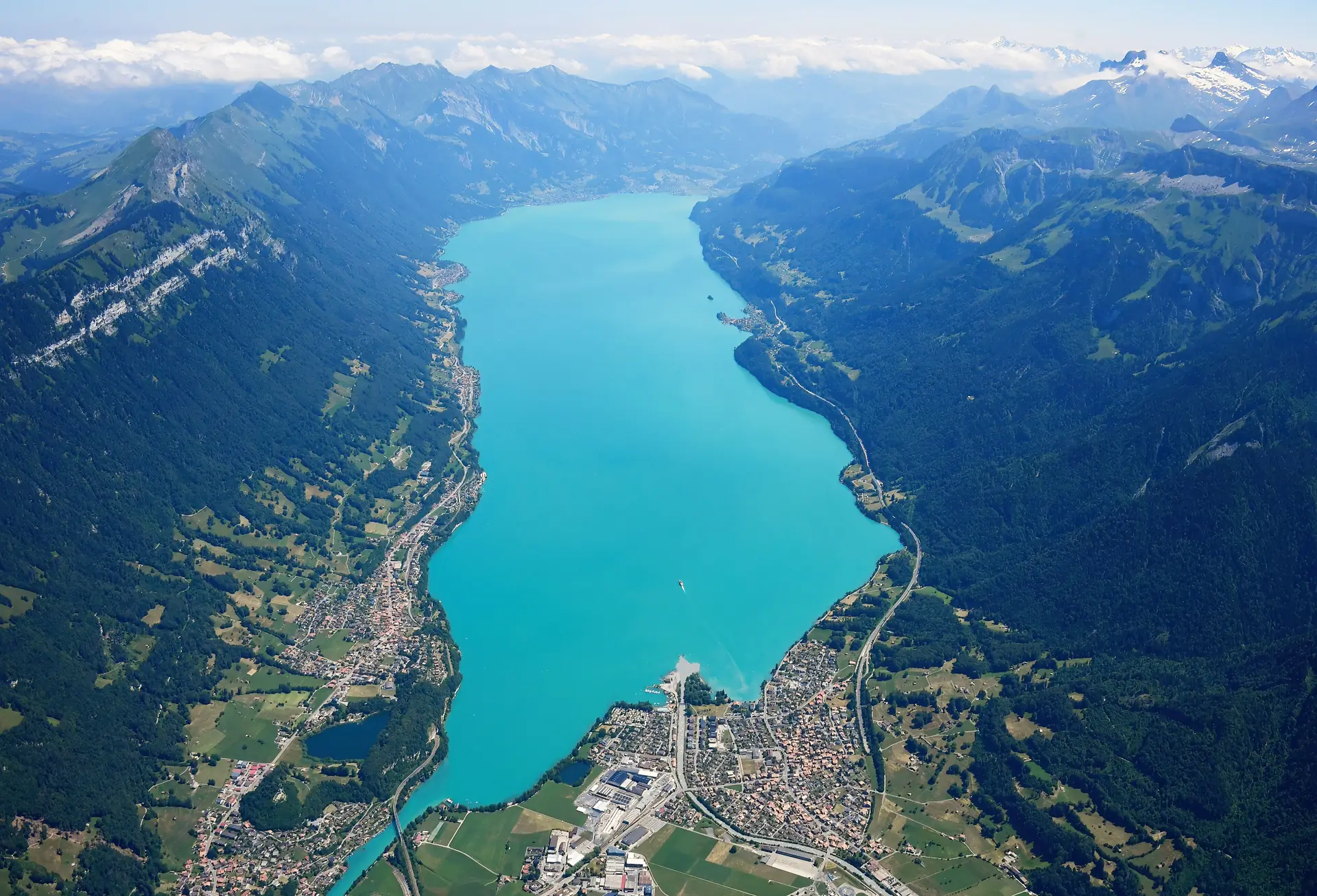 Aerial view of turquoise Lake Brienz between steep wooded mountainsides, looking north-east from above Interlaken