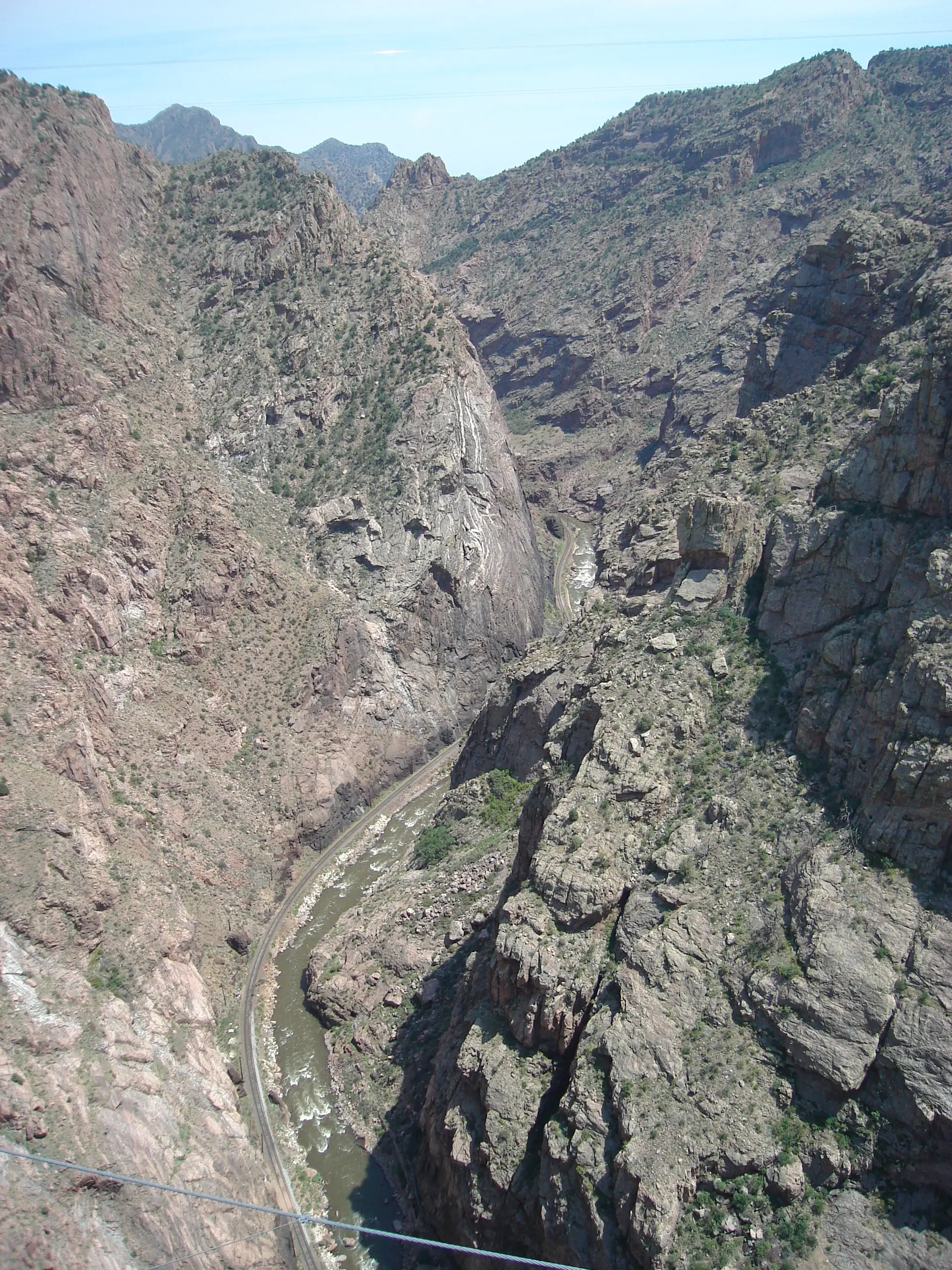 Blick senkrecht von der Royal Gorge Bridge hinunter auf den Arkansas River und die Bahnlinie am Grund der Schlucht