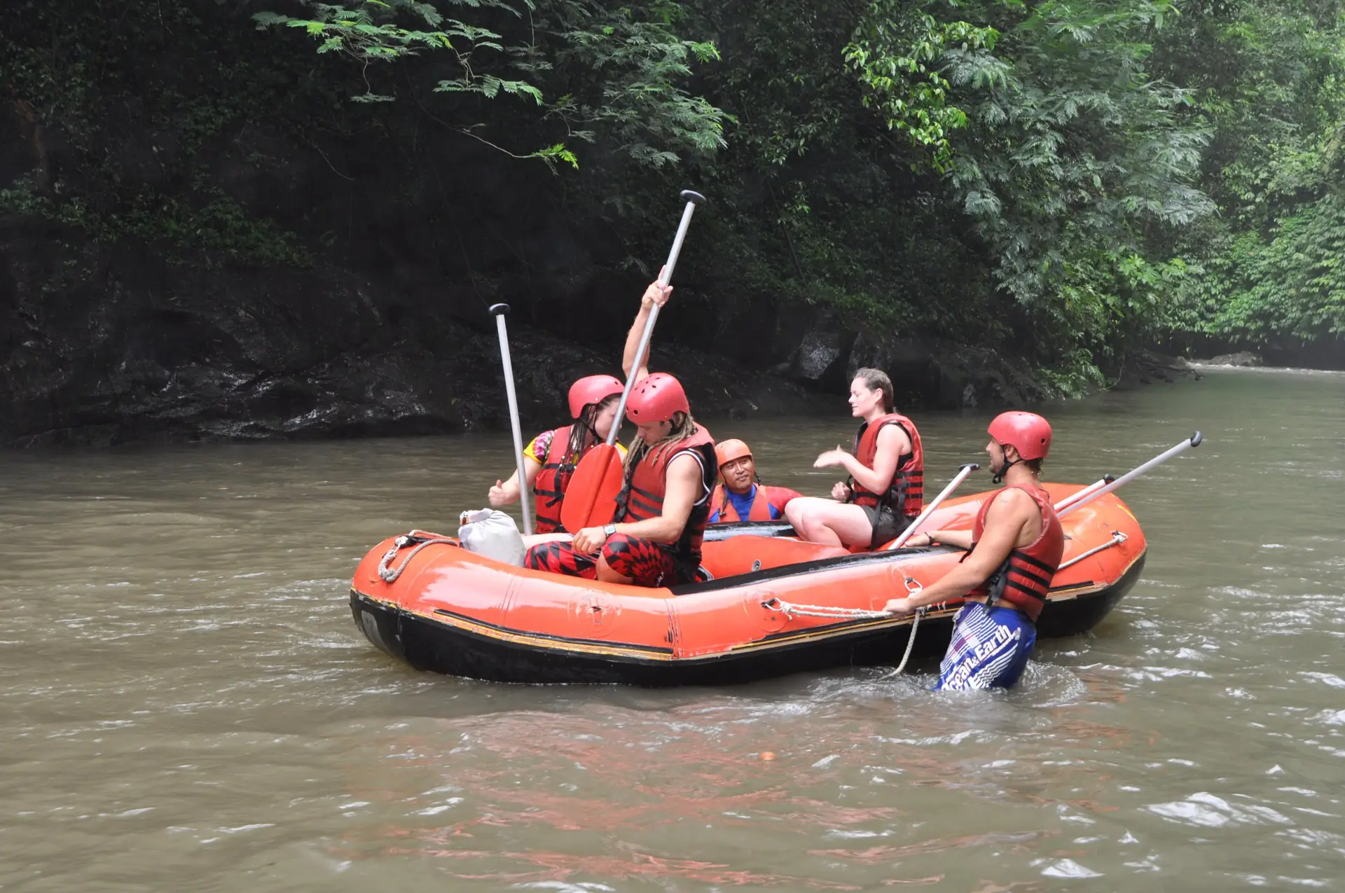 A raft with helmeted paddlers on the Ayung River in a jungle gorge near Ubud
