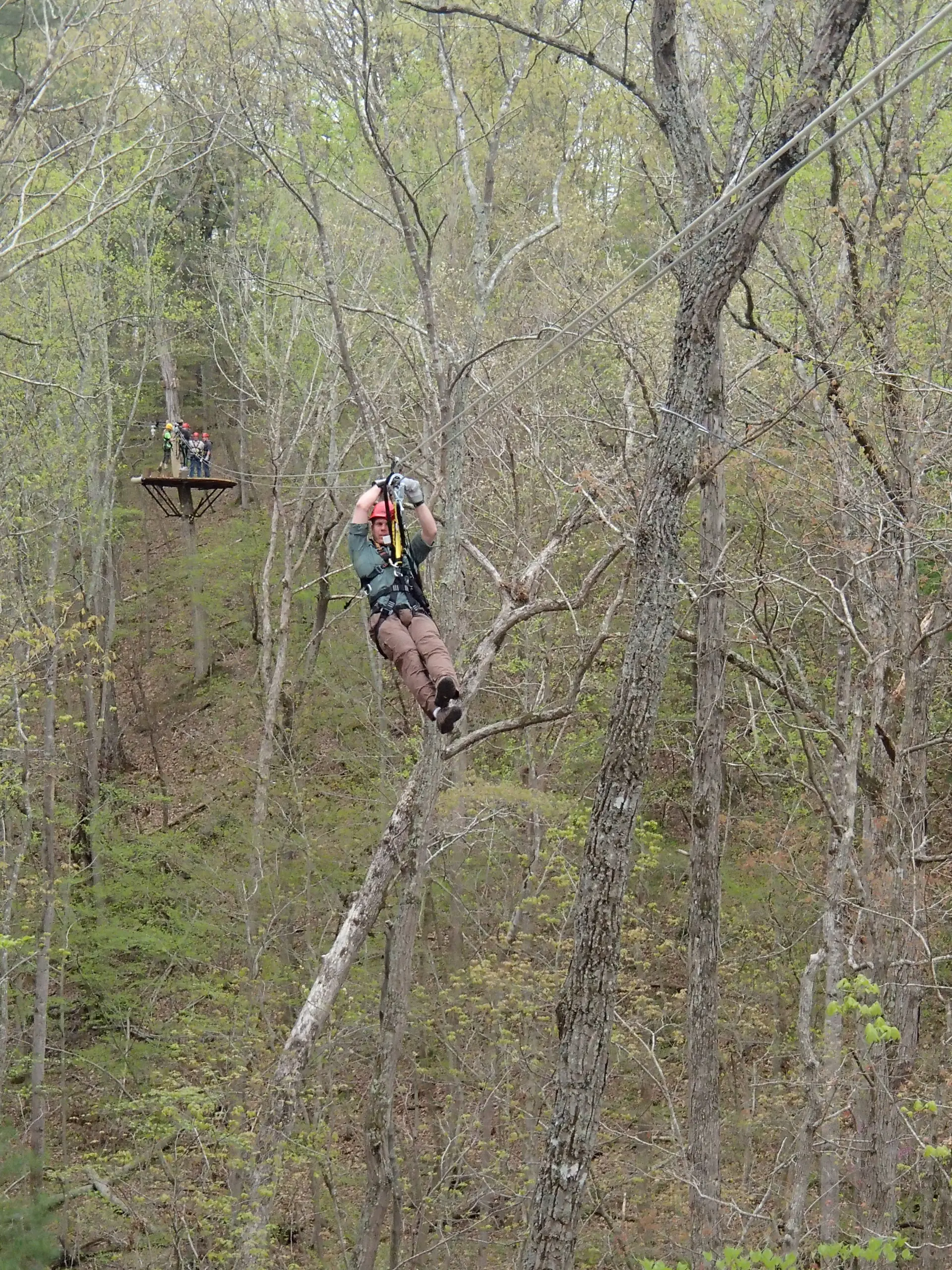 A rider on a zipline through forest