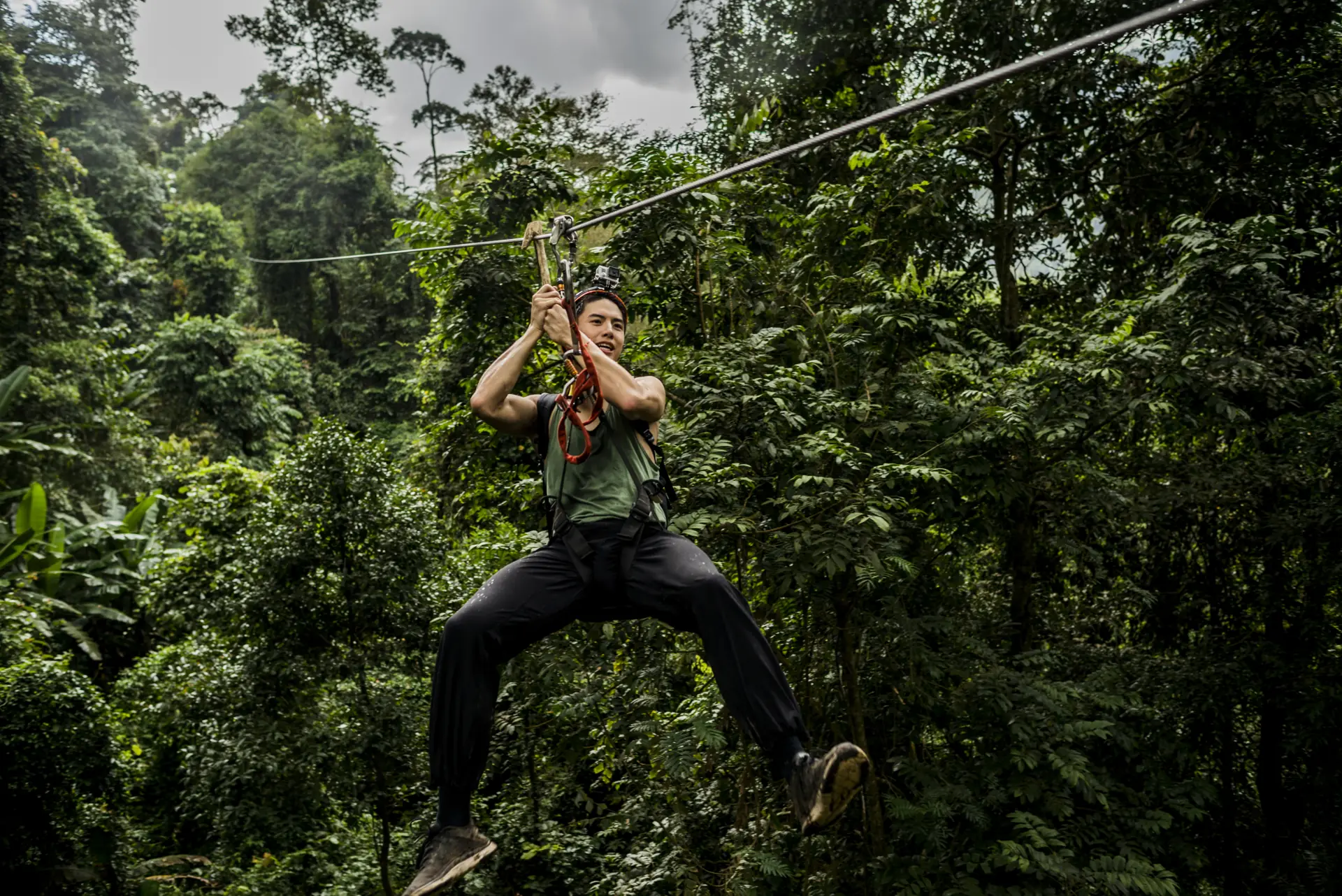 Ein Fahrer hängt am Zipline-Seil über dichtem grünem Blätterdach (Symbolbild, nicht Gatorland)