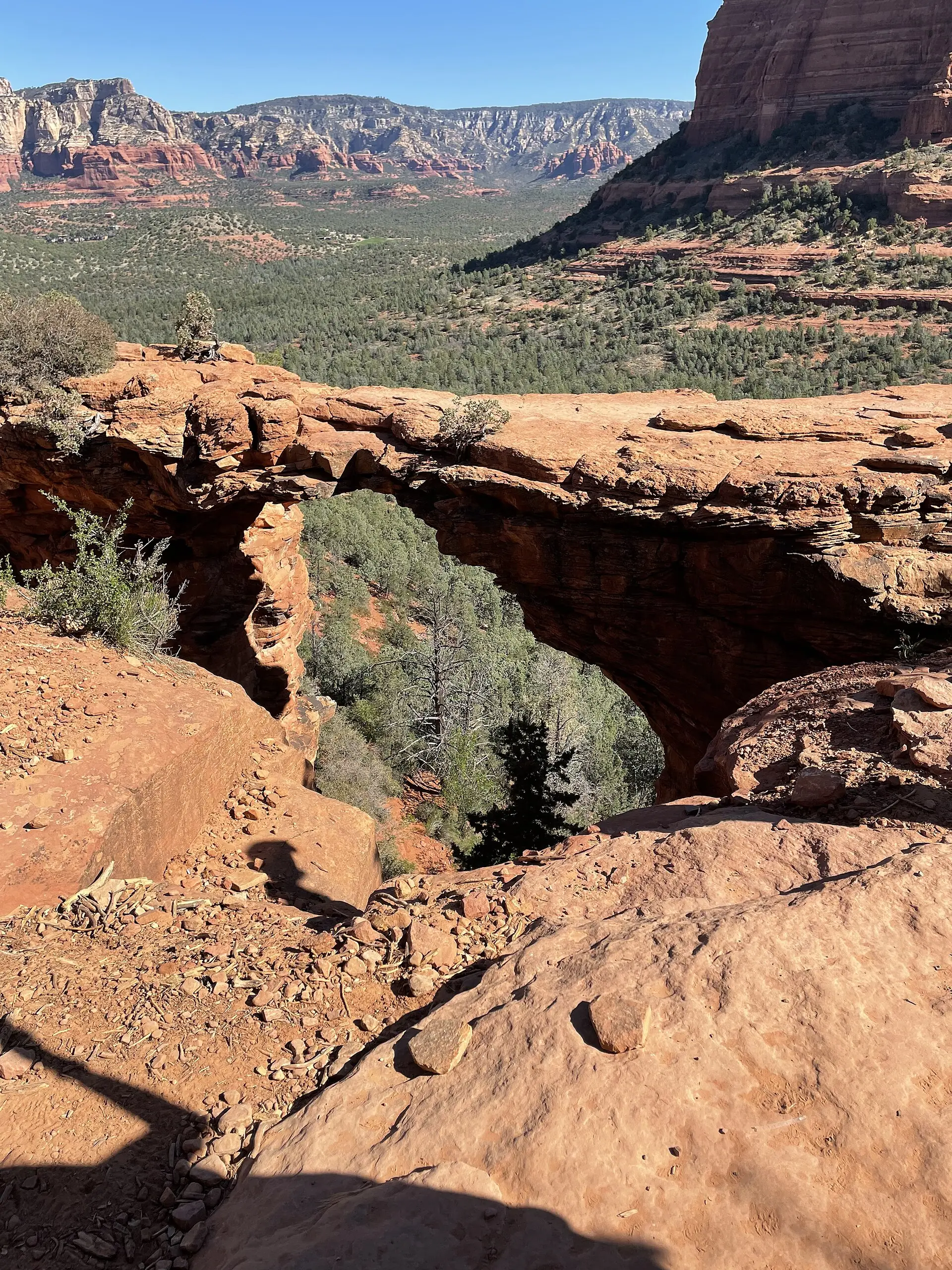 Ein Wanderer steht auf dem natürlichen Sandsteinbogen Devil's Bridge über dem roten Felsland bei Sedona