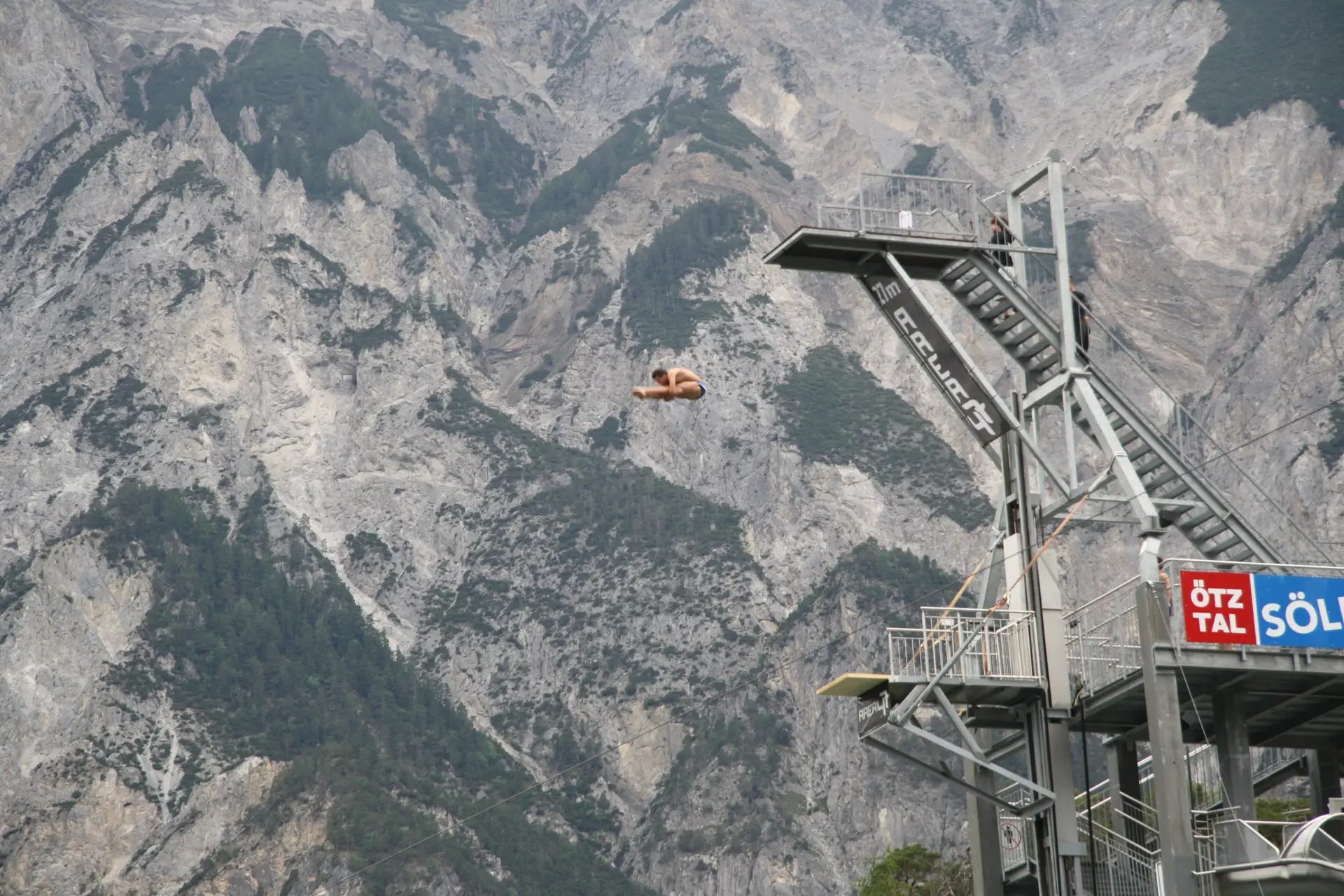 Der Sprungturm der Area 47 im Ötztal während eines Klippenspring-Wettbewerbs, ein Springer in der Luft
