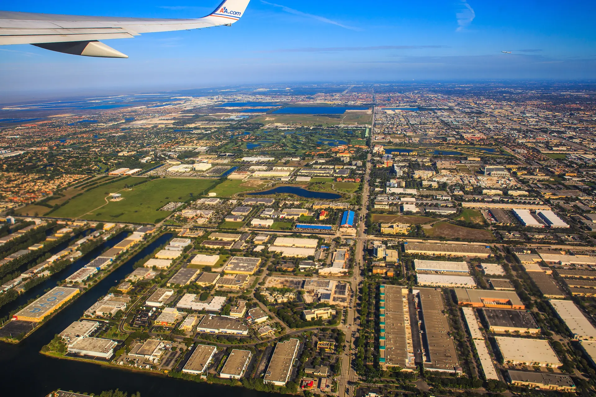 View past an airliner wing over South Florida, canals and the Everglades stretching to the horizon
