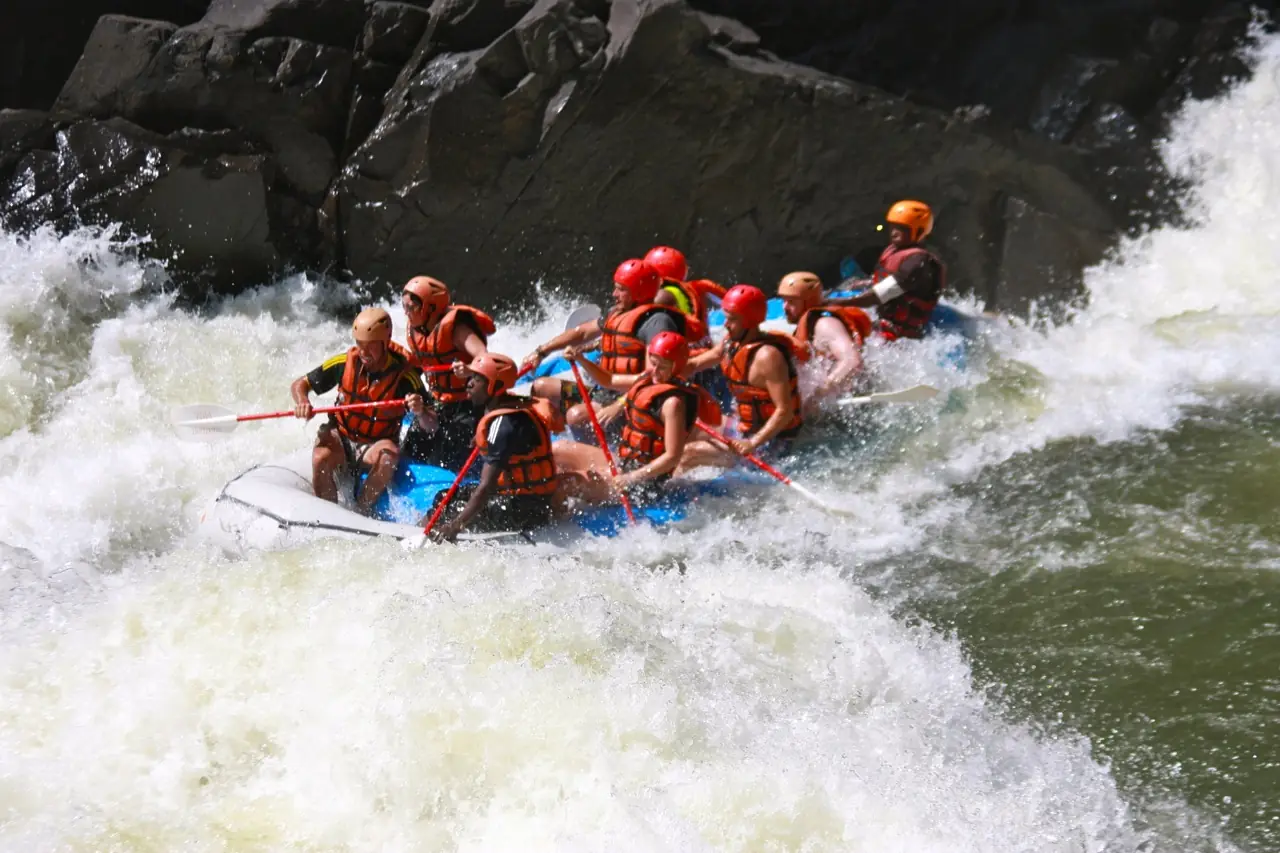 A raft full of paddlers in helmets crashing through a grade 5 rapid on the Zambezi