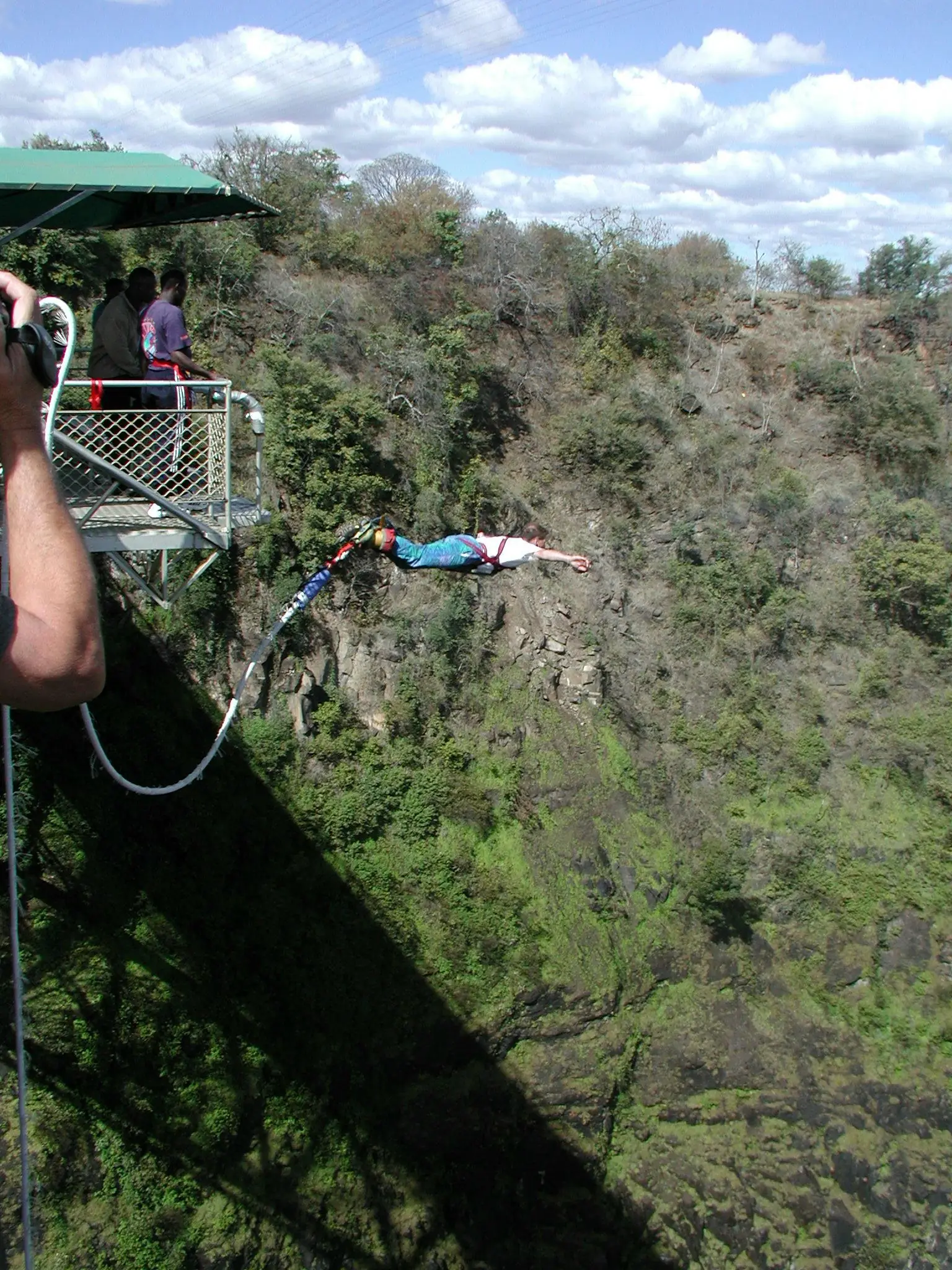 A bungee jumper in freefall beneath the steel arch of Victoria Falls Bridge above the Batoka Gorge