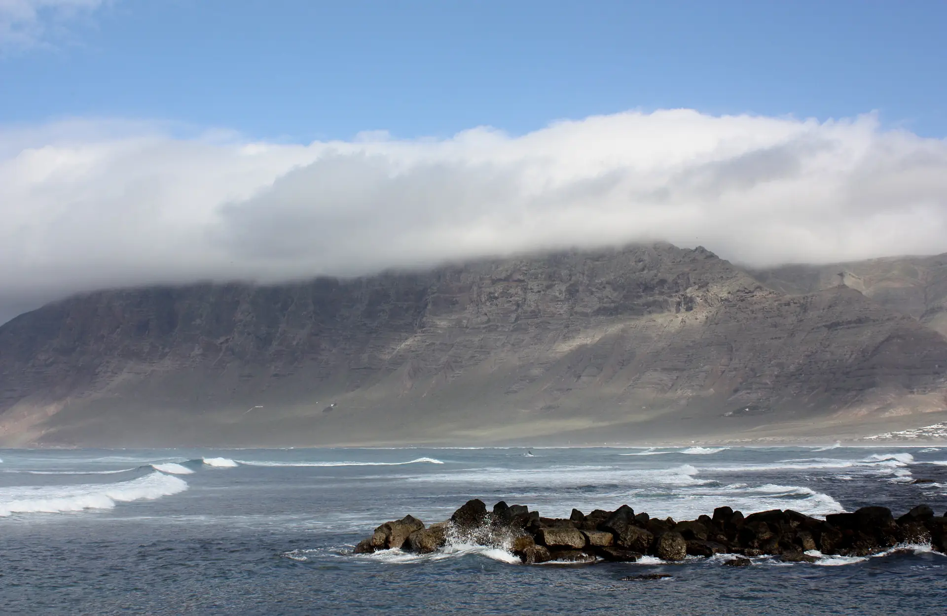 The Risco de Famara, a 600-metre wall of rock rising straight out of the Atlantic behind the surf at Caleta de Famara