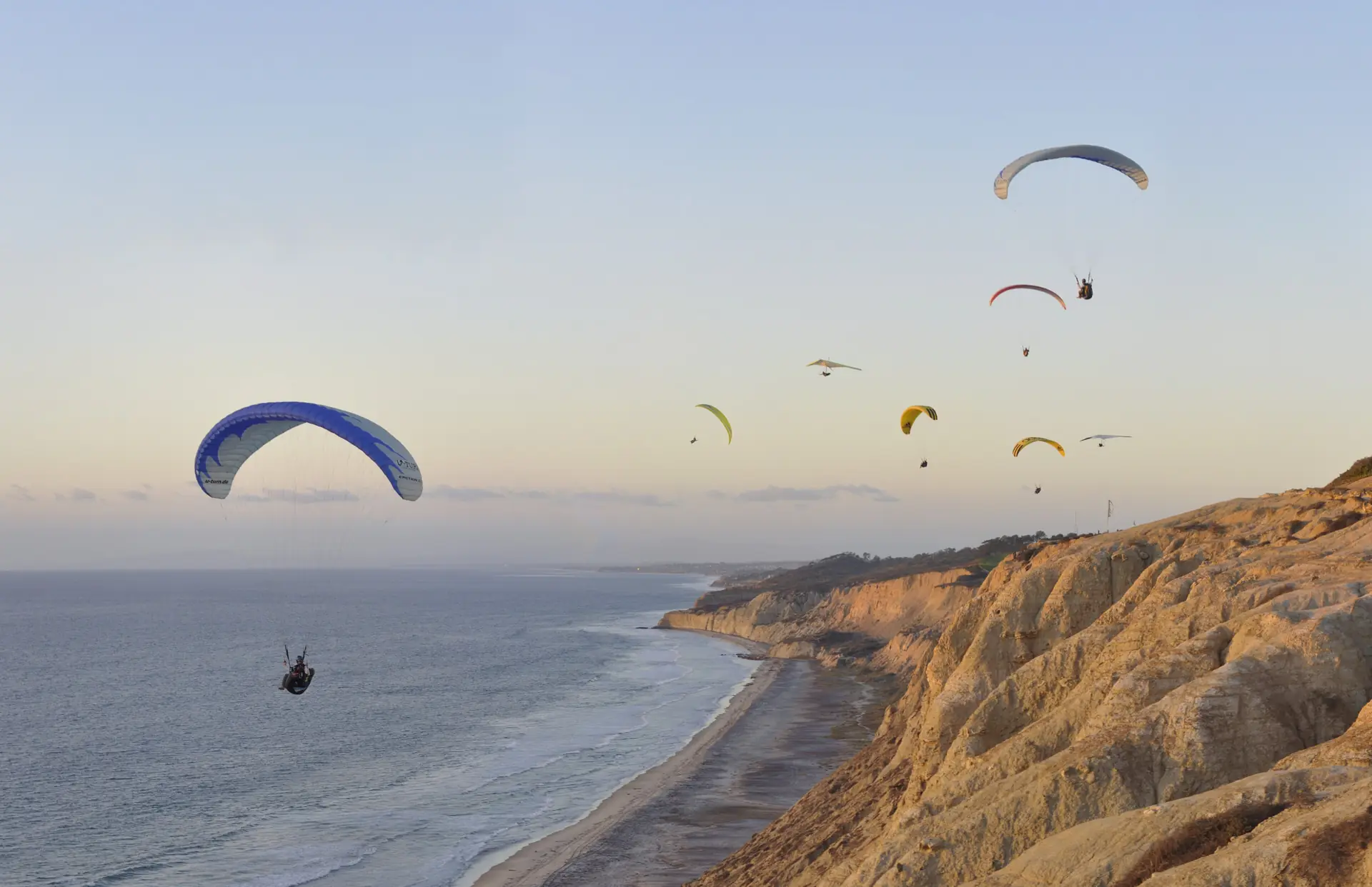 Paragliders over the Torrey Pines cliffs with Black's Beach and the Pacific below