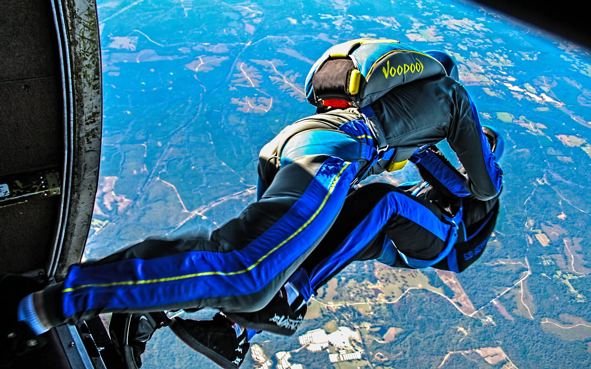 Ein Tandem-Fallschirmpaar im freien Fall vor blauem Himmel