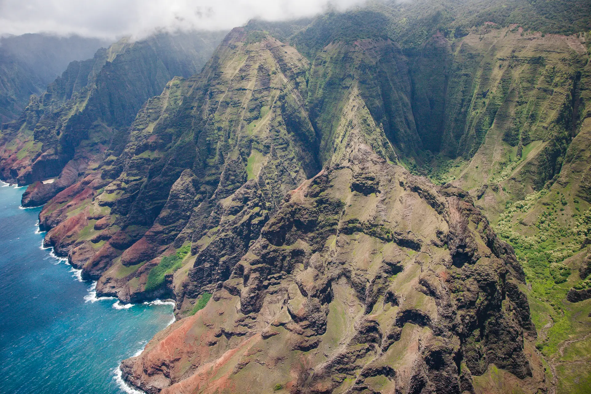 Die gefalteten grünen Klippen der Nā-Pali-Küste fallen steil in den blauen Pazifik