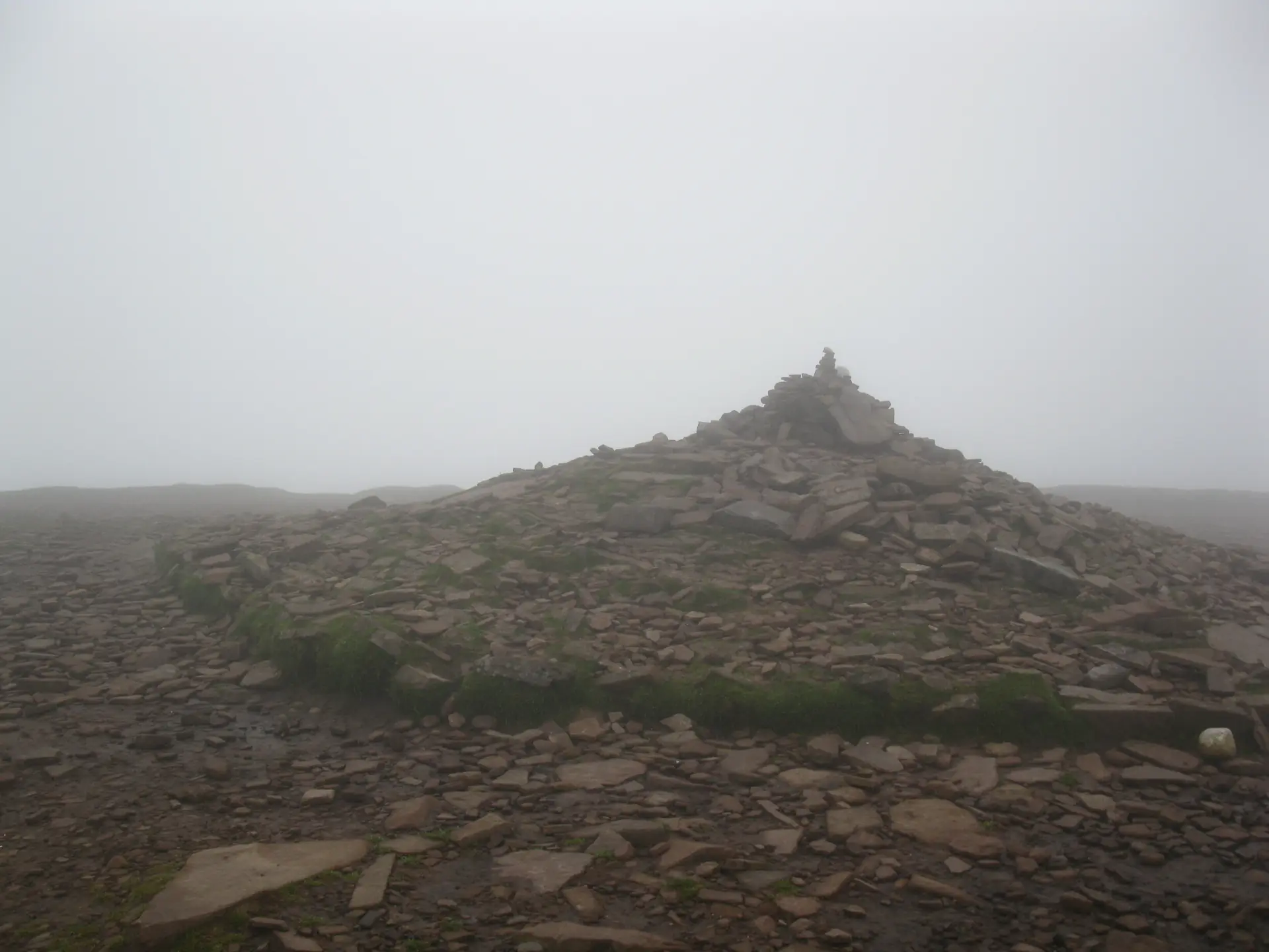 Der Gipfel des Pen y Fan mit Steinmann in Wolken