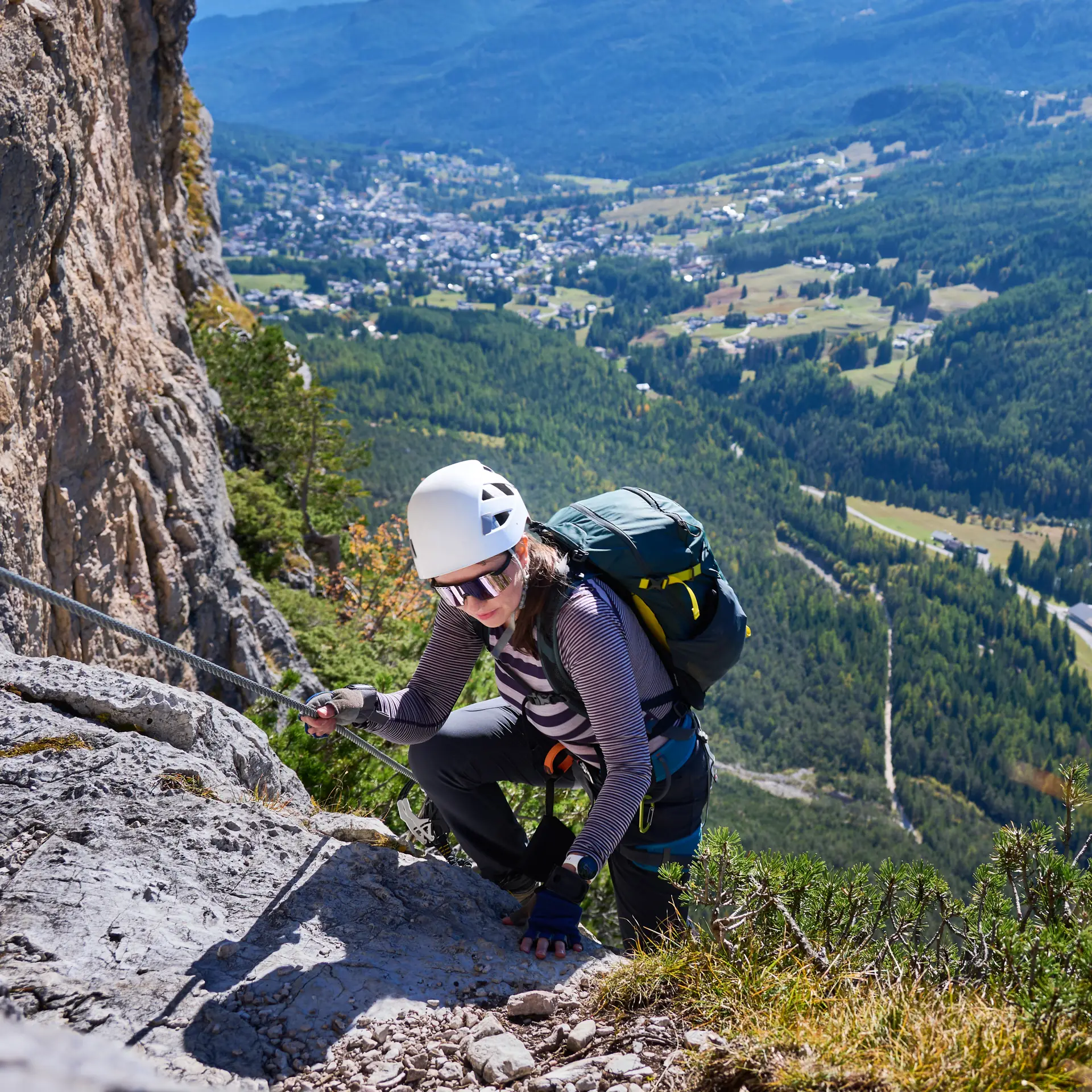 Ein Kletterer am Klettersteig, ins Stahlseil eingehängt, auf Eisenstufen eine senkrechte Felswand hinauf (Symbolbild, nicht die Skylodge-Route)