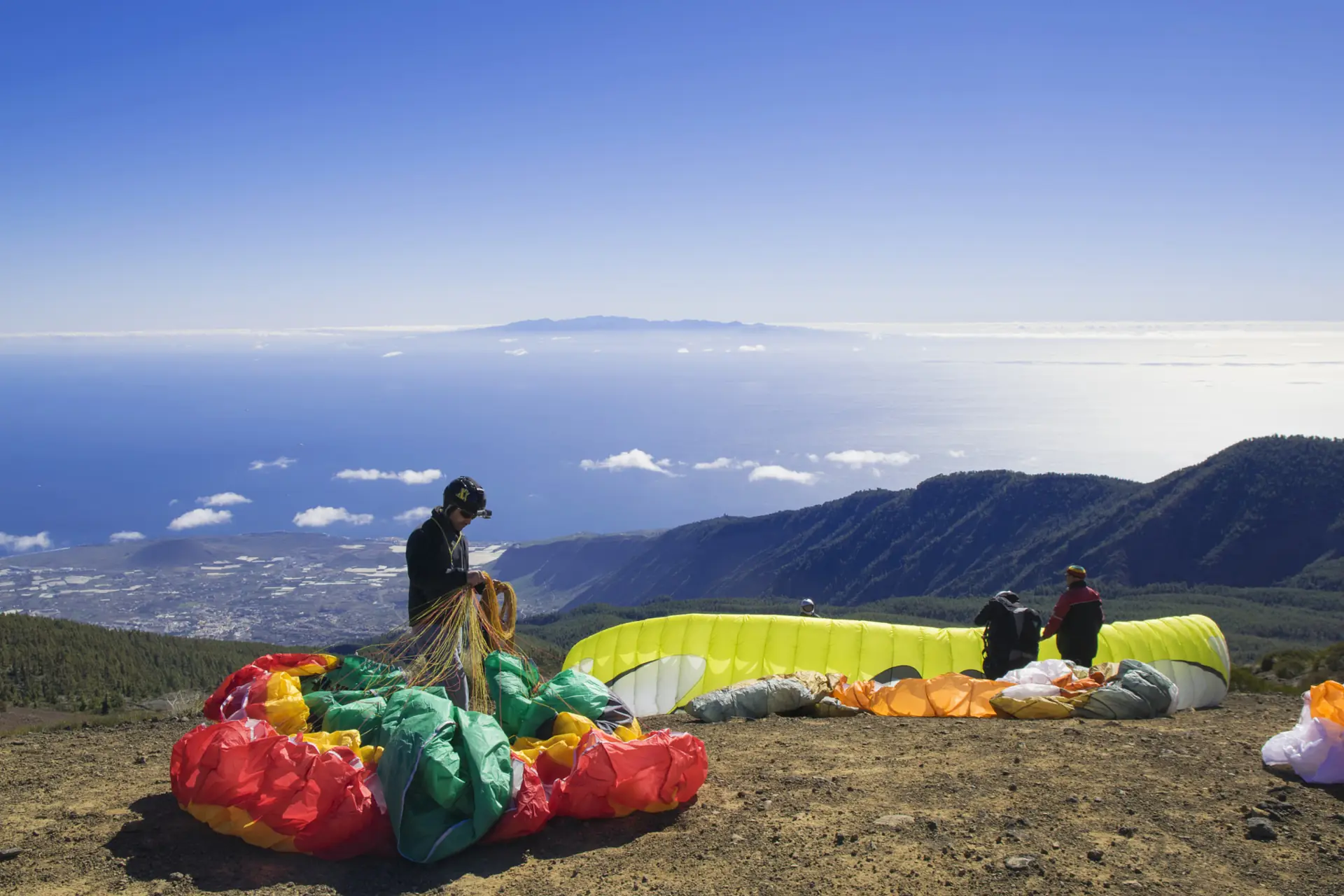 Paraglider pilots laying out their wings on a cliff-top launch above the sea (symbolic image, not Famara)