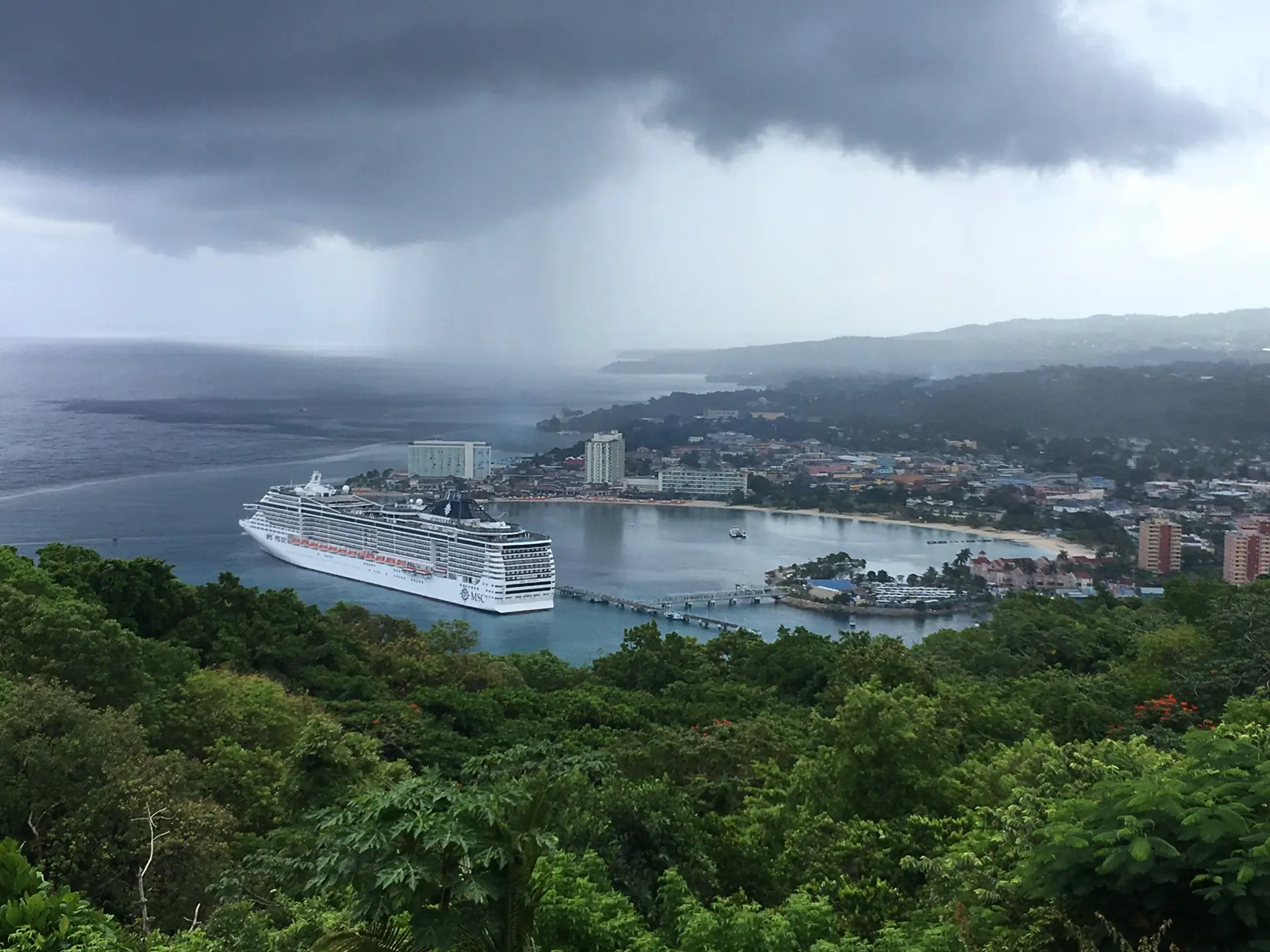 The view down from Mystic Mountain over Ocho Rios bay with a cruise ship at the pier and a rain squall coming in
