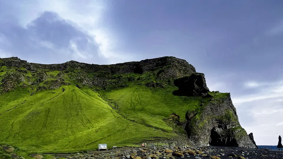 Reynisfjall rising over the black sand of Reynisfjara with the Reynisdrangar sea stacks offshore