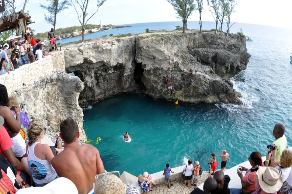 The limestone cliffs of the West End at Negril with the crowd at Rick's Café watching a jumper