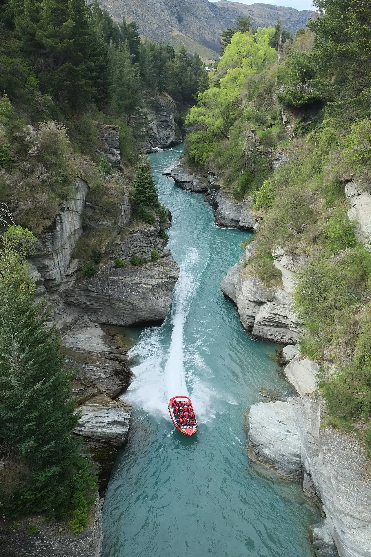 The narrow Shotover River canyon at Arthur's Point seen from above, a red jetboat far below between the rock walls