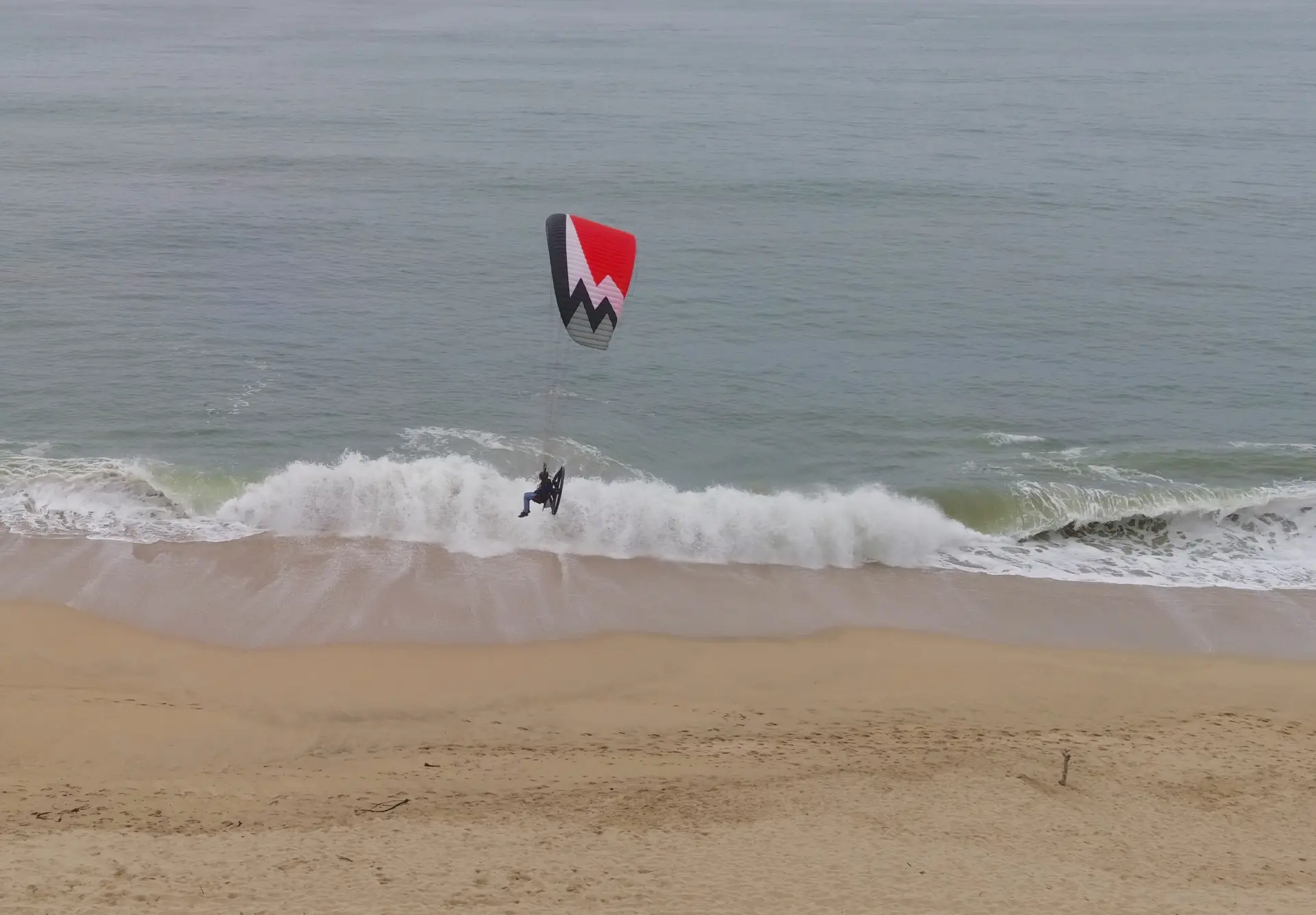 A paraglider skimming the surf on a California beach