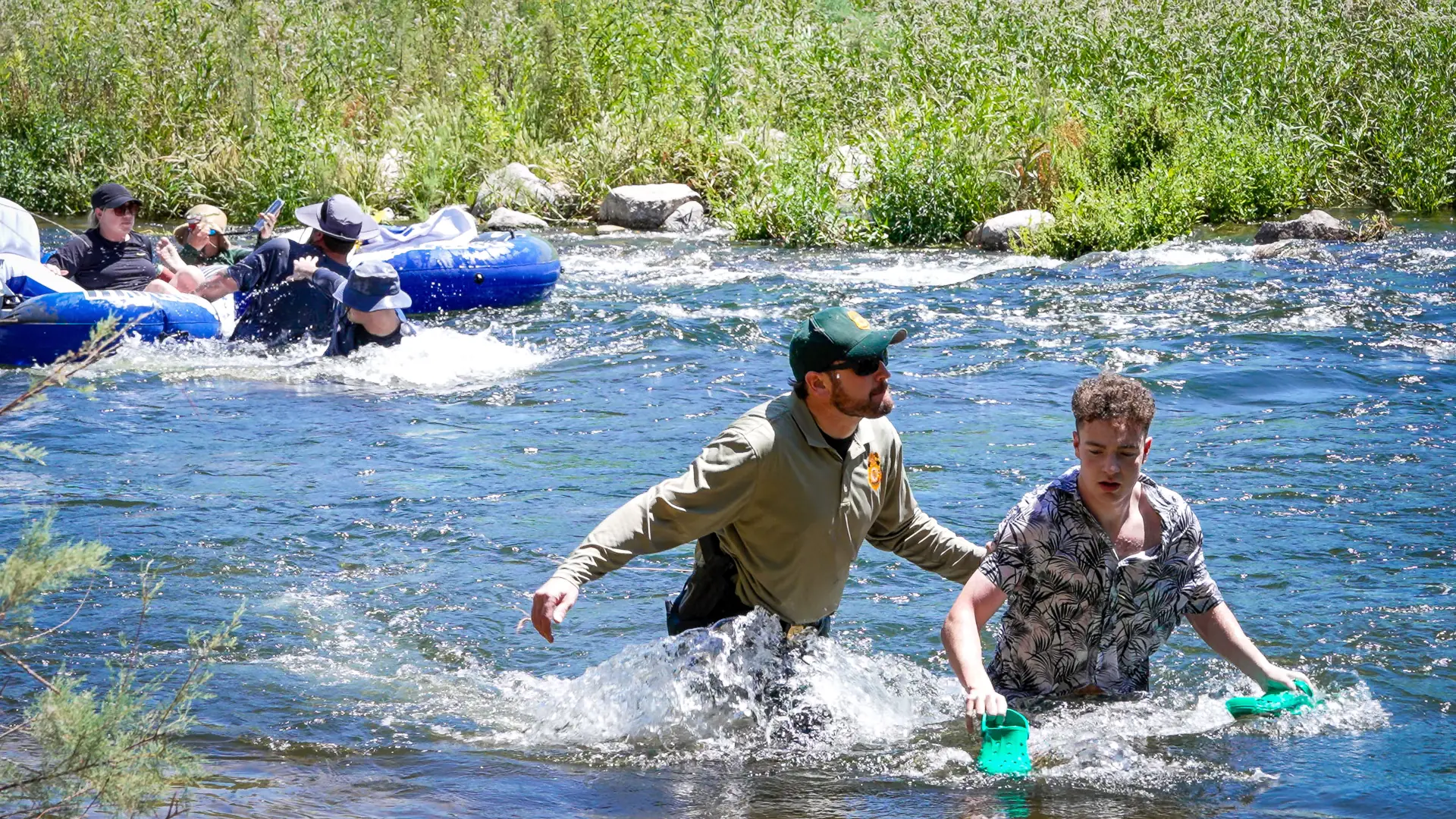 Tubers float a riffle on the Lower Salt River while a Forest Service officer wades beside them