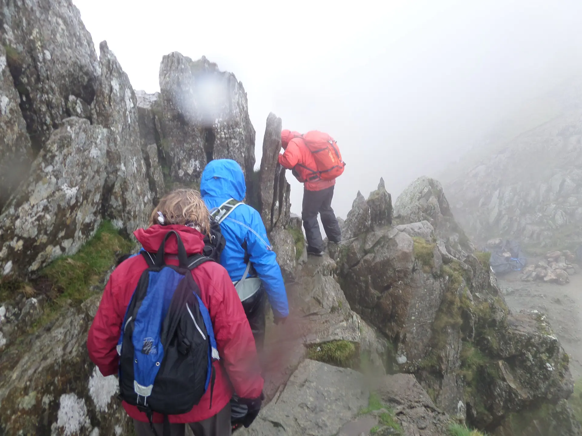 Wanderer klettern im Nebel über die Felsen der Striding Edge