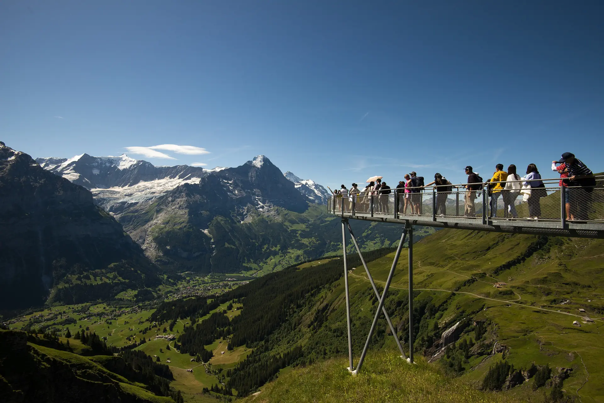 Visitors on the First Cliff Walk platform jutting out over the Grindelwald valley with the Alps behind