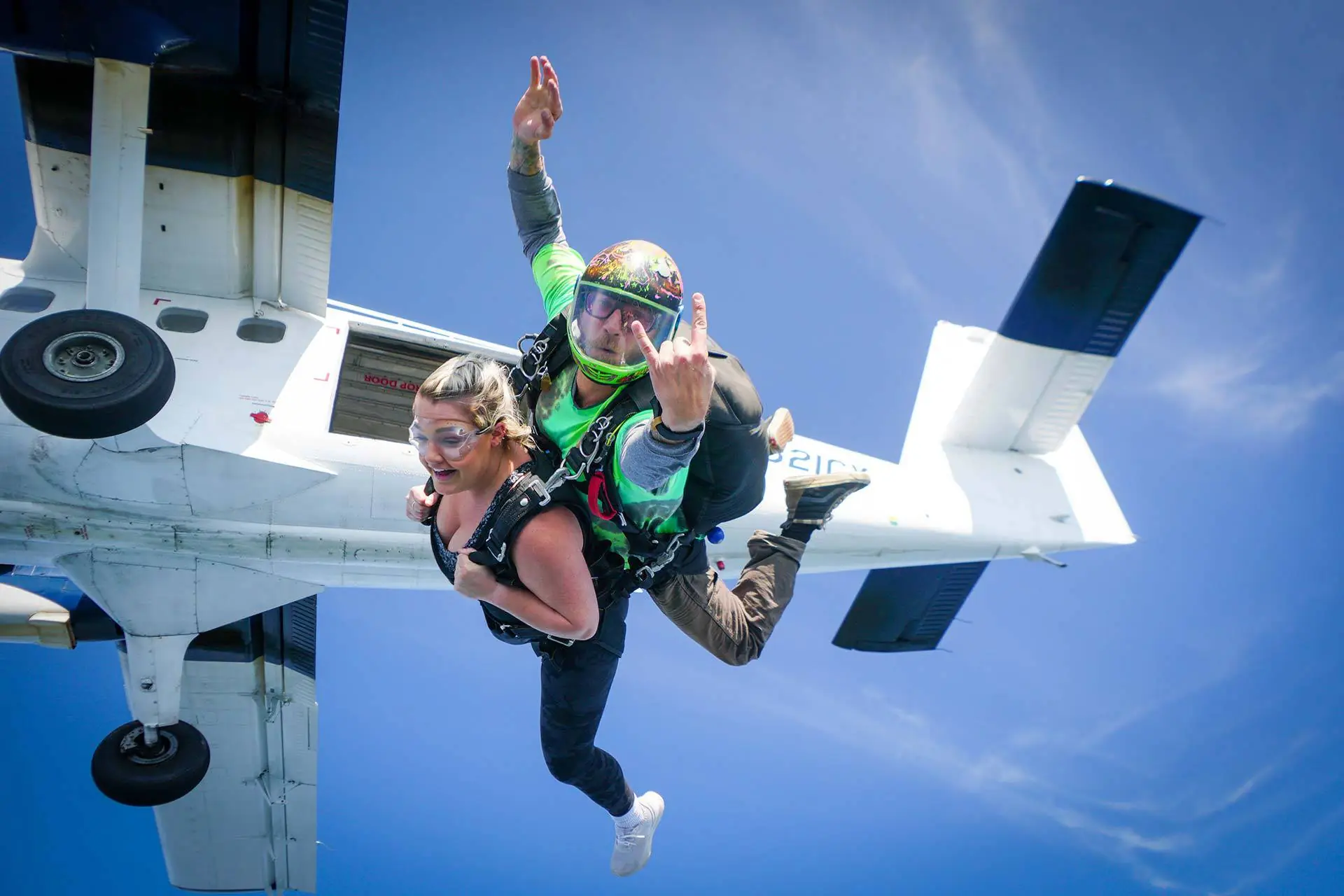 A tandem pair leaving the door of a small aircraft into blue sky, the instructor's arms spread (symbolic image, not Bantayan)