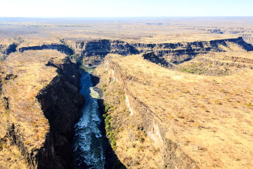 Oblique aerial view of Victoria Falls dropping into the Batoka Gorge with the Zambezi winding away beyond