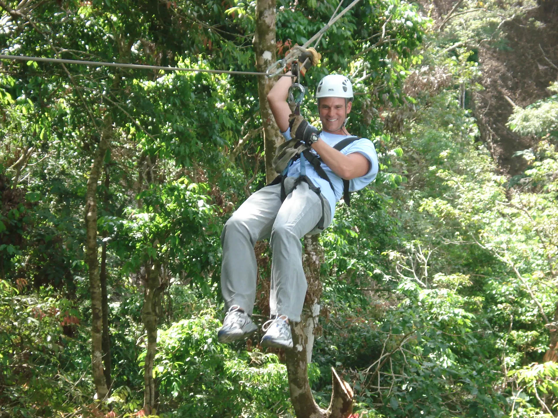 A rider on a zipline high above the Costa Rican rainforest canopy
