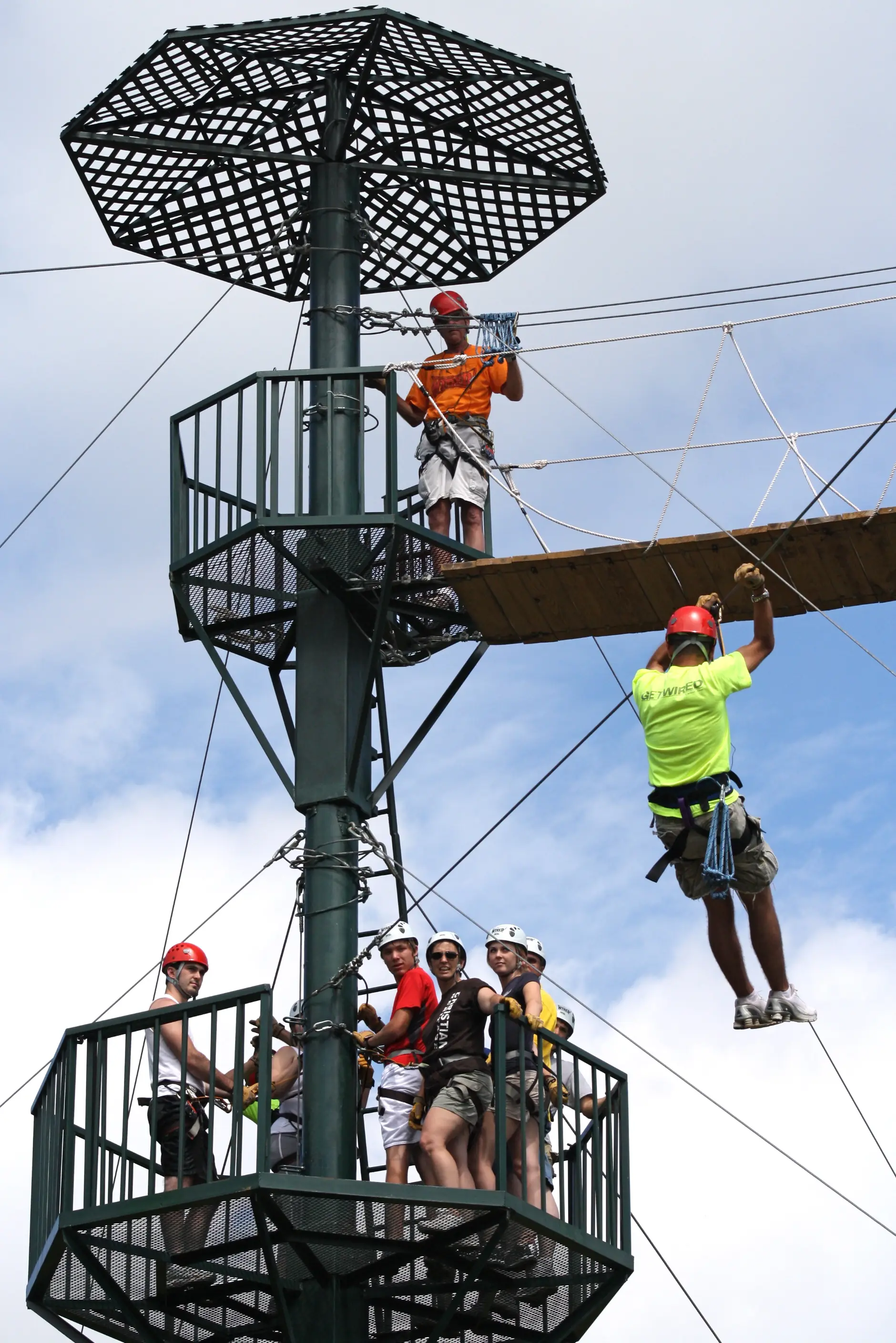A rider on a zipline against a green slope